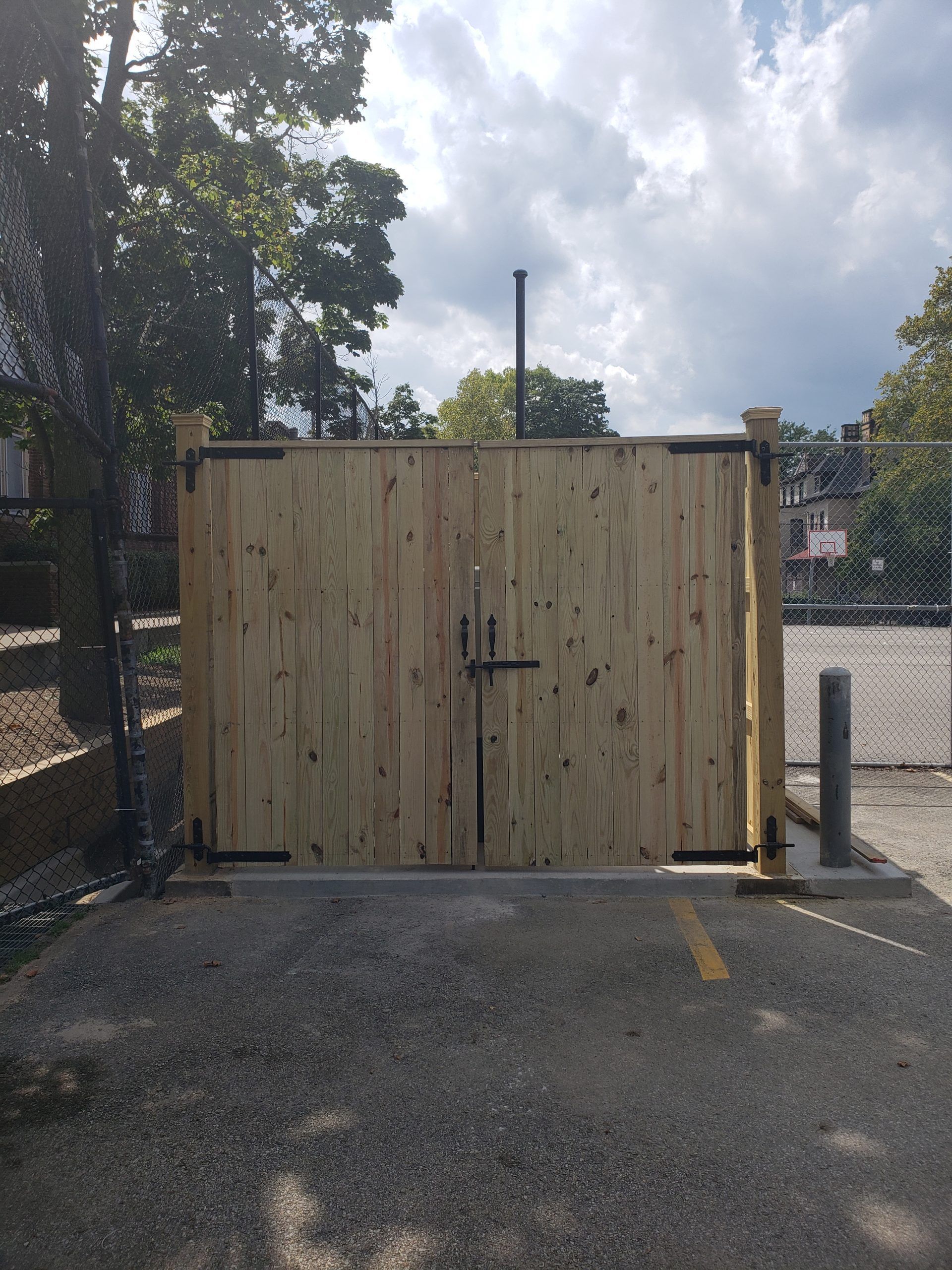 Wooden double doors on a gravel area, part of a fence.