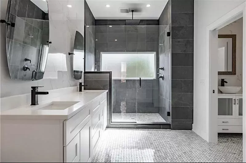Modern bathroom with a white vanity, gray tile shower, and mosaic floor.