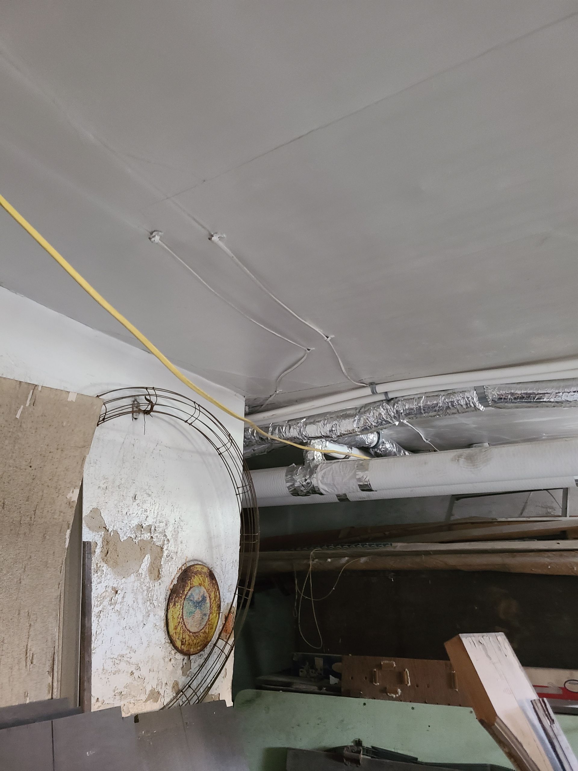 Ceiling and wall with exposed wiring and partially demolished structures. Yellow wire runs along the ceiling.
