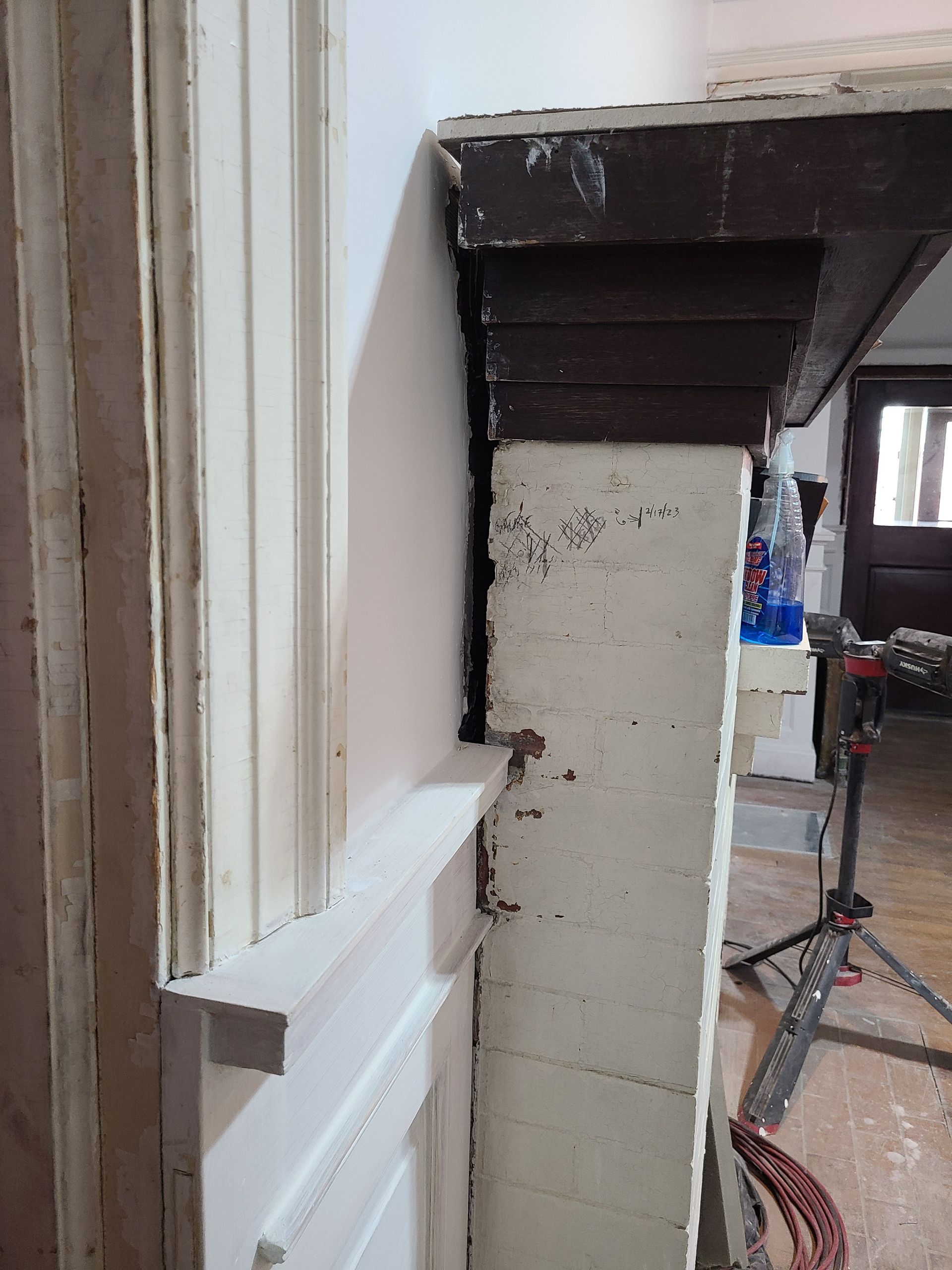 Partial view of a doorway. White door with molding on the left. Dark wood header above a textured wall.