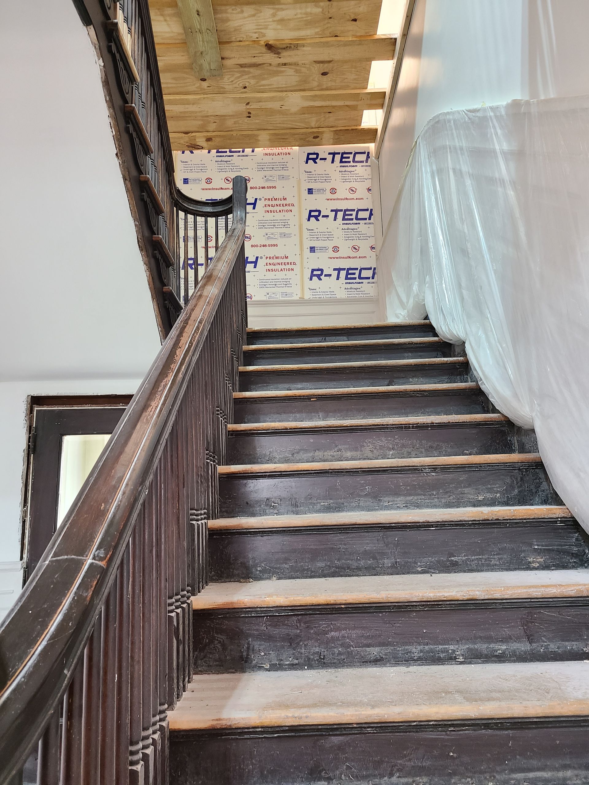 Wooden staircase with dark brown handrail and steps, construction in progress.