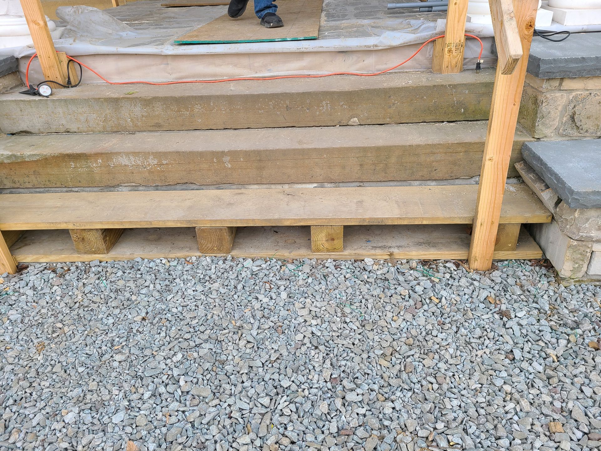 Concrete steps with wooden supports and gravel ground.