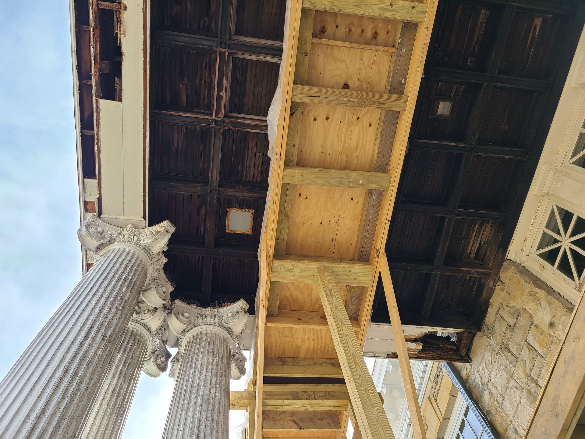 View up at columns and ornate ceiling with scaffolding.