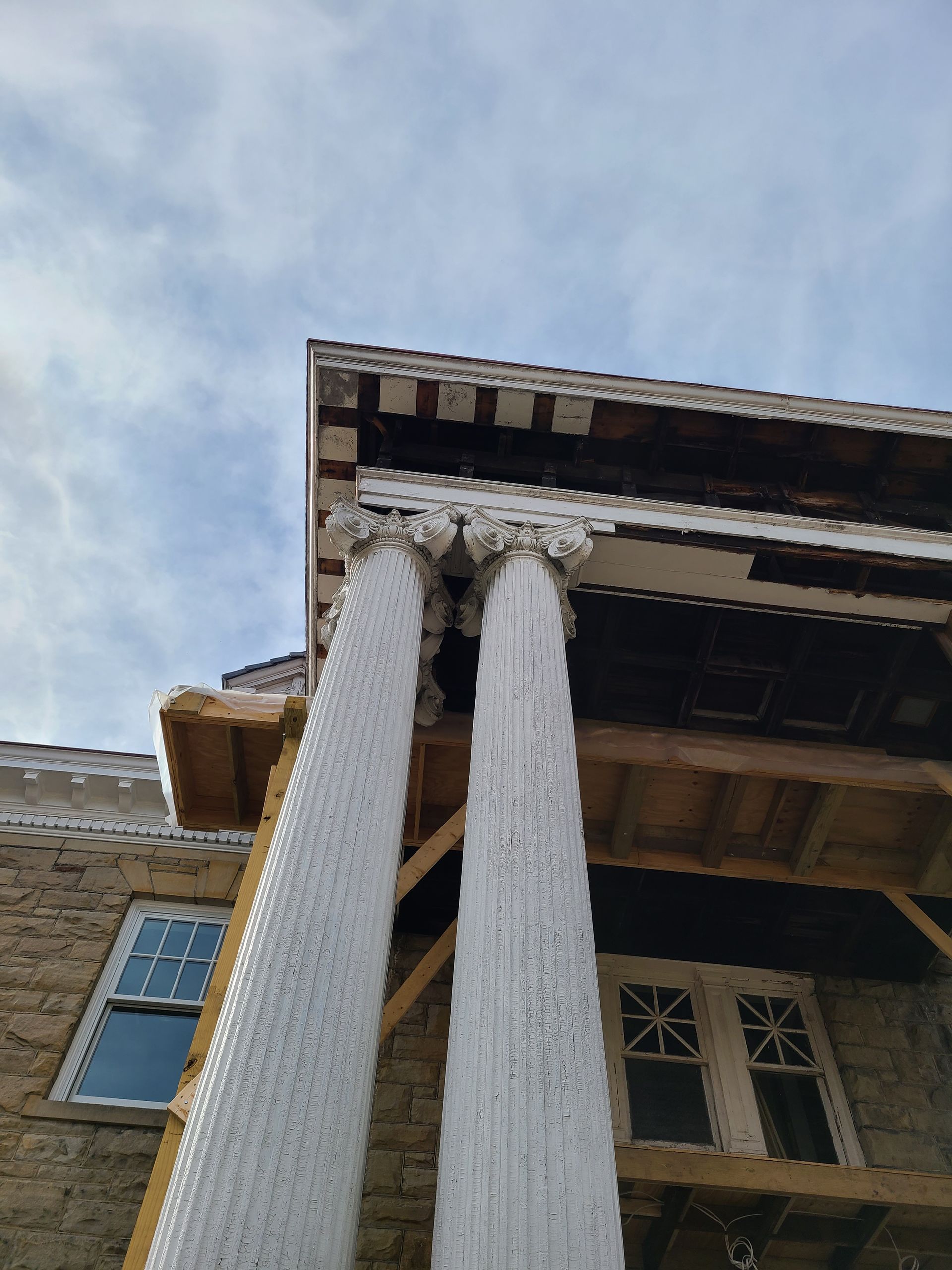 Building with two white fluted columns supporting a roof, blue sky in the background.