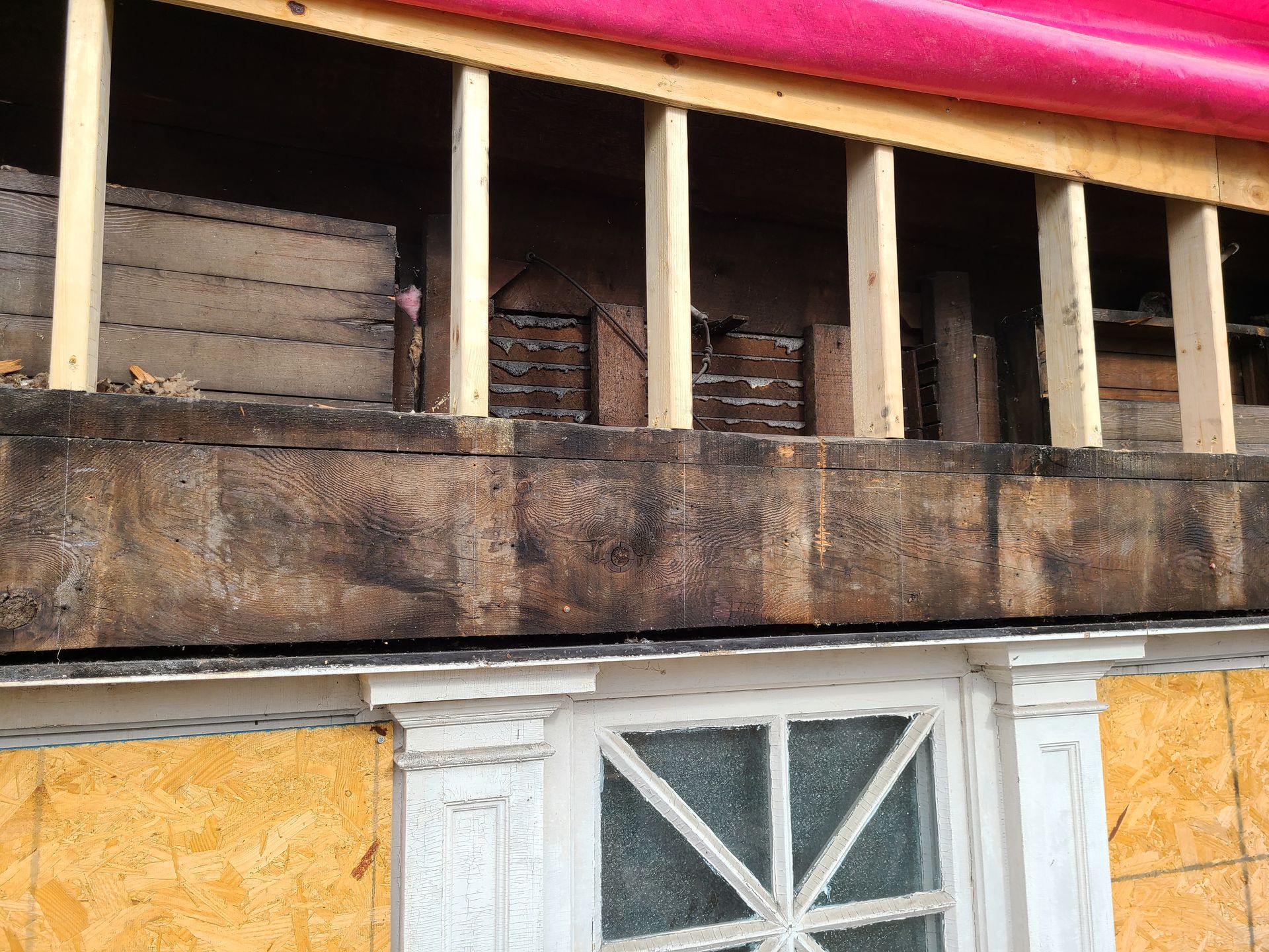 Exterior wall of a building under construction, showing wooden beams and partially exposed interior.