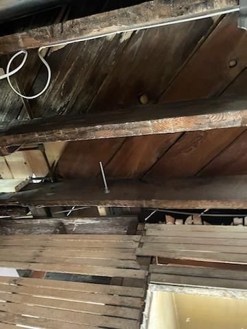Wooden ceiling showing exposed beams and old wiring.