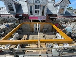 Construction site: House exterior under renovation with scaffolding, wooden frame, and a worker.