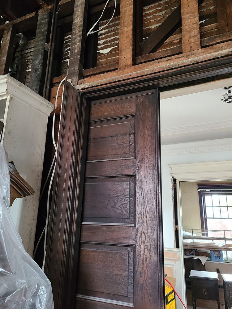 Brown wooden door in a room under construction, with exposed beams and unfinished walls.