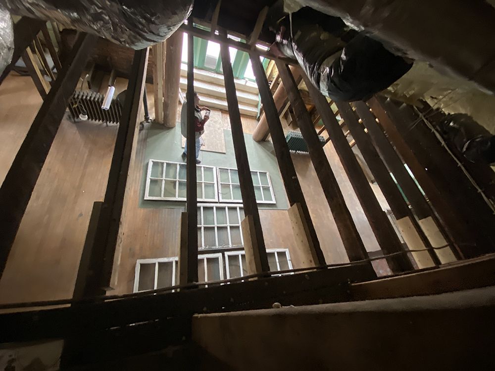 Looking down into a building under construction. Workers stand by new window frames.
