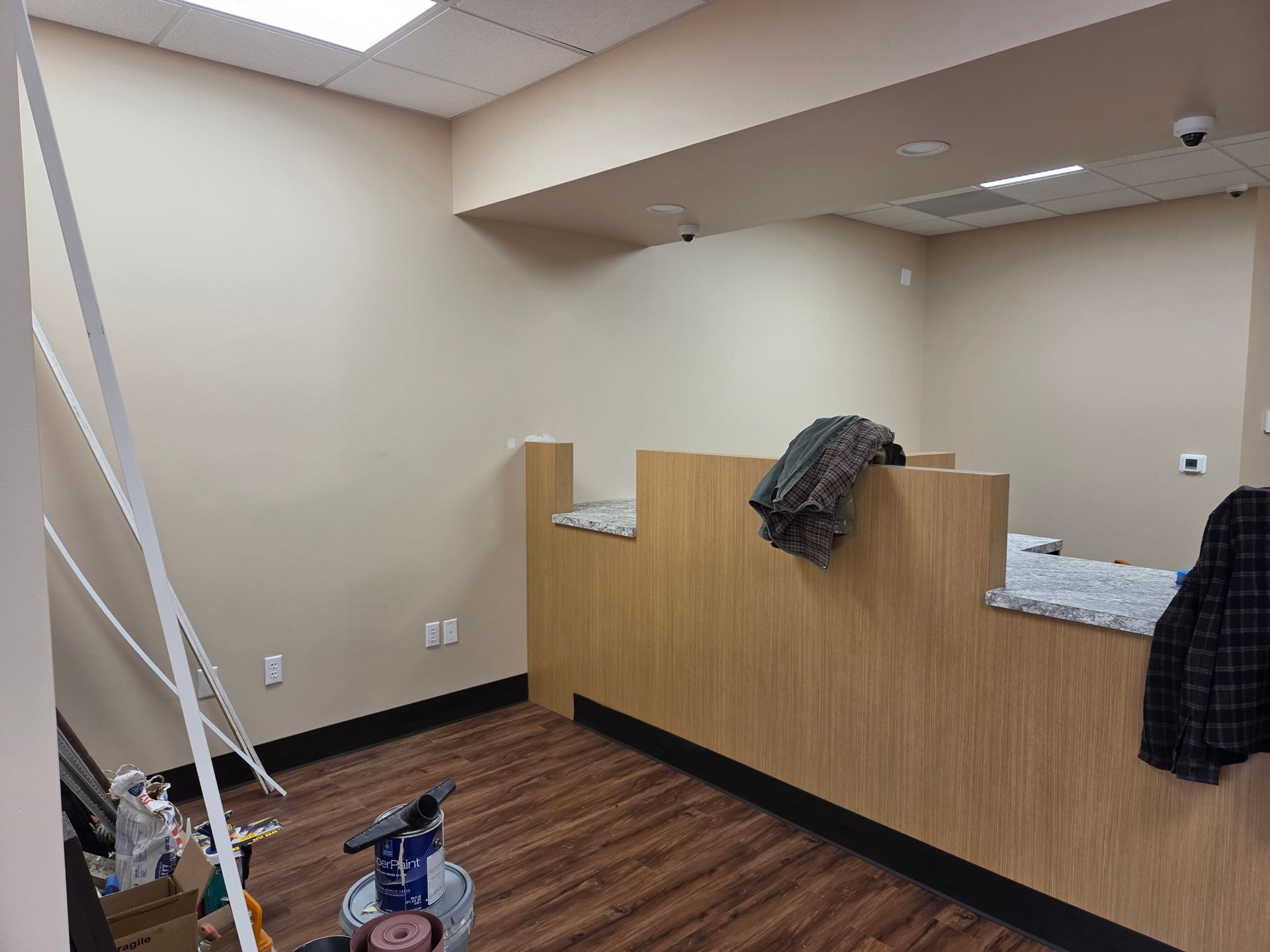 Interior of a room with a wooden counter, dark flooring, and beige walls; a few tools visible.