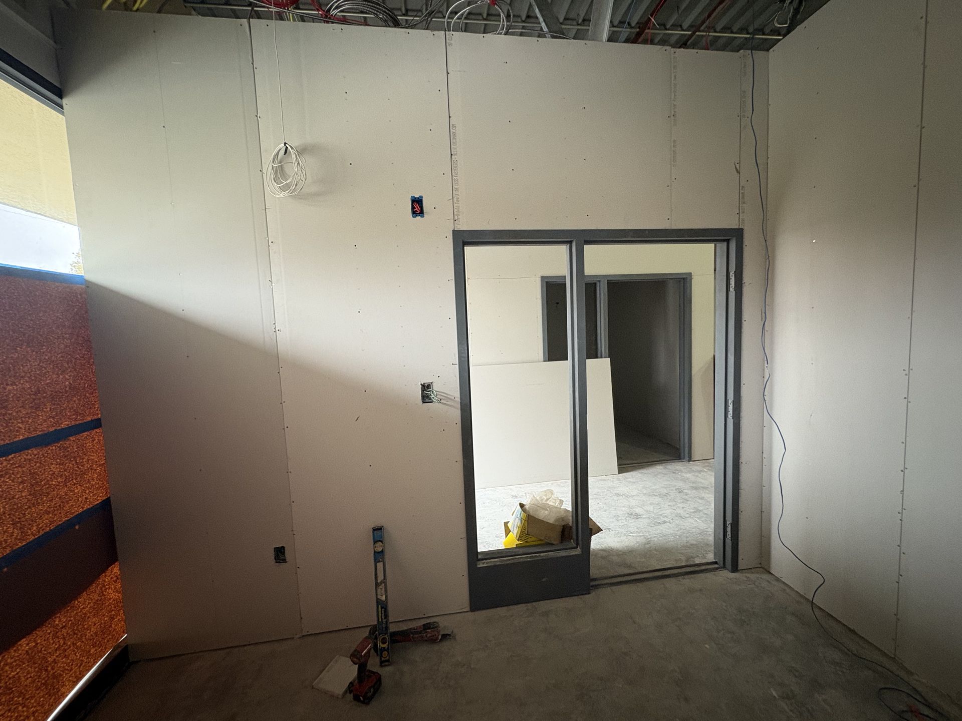 Interior view of unfinished room with drywall and doorway.