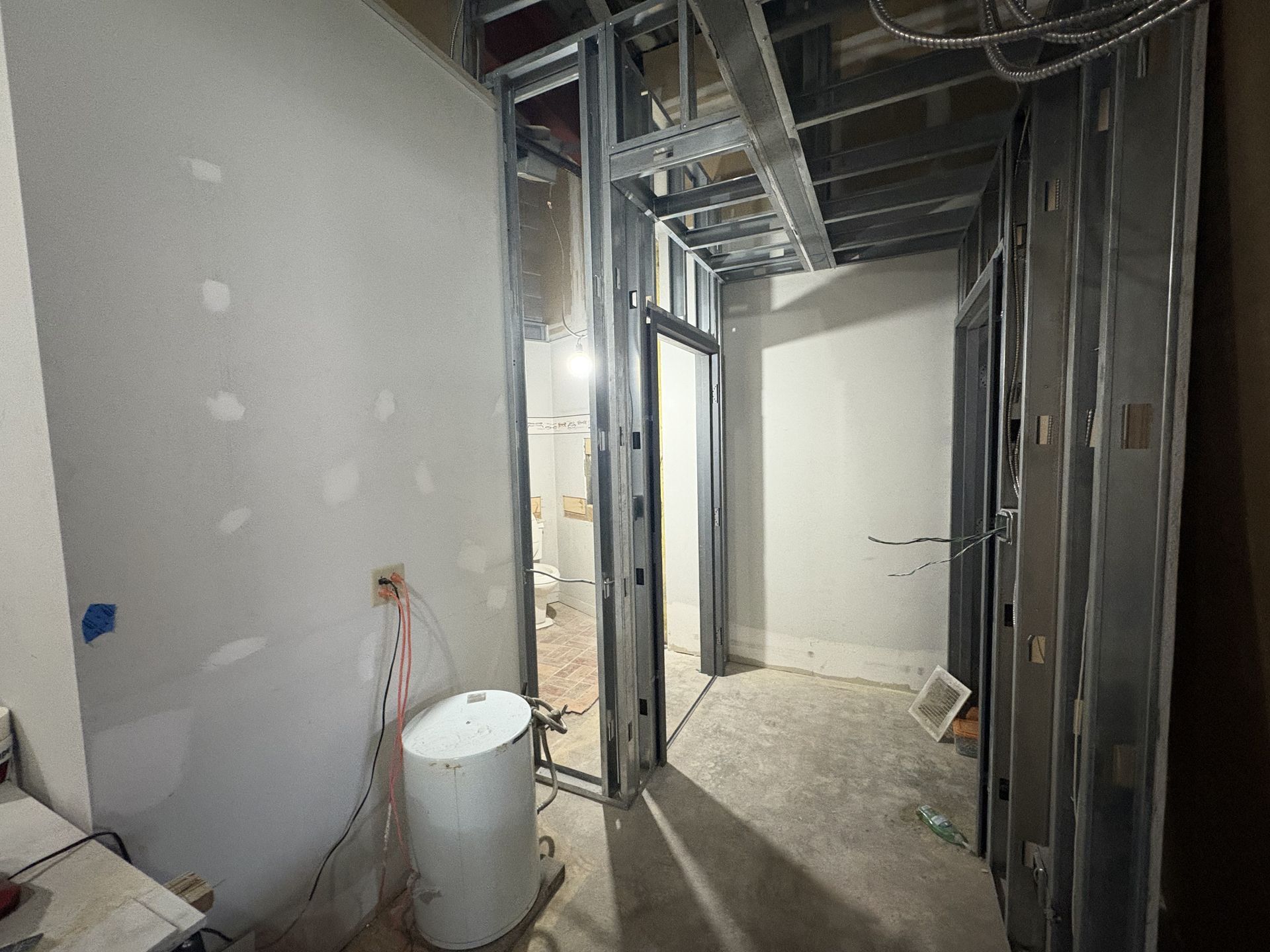 Interior construction site with metal framing, exposed wiring, and partially finished walls.