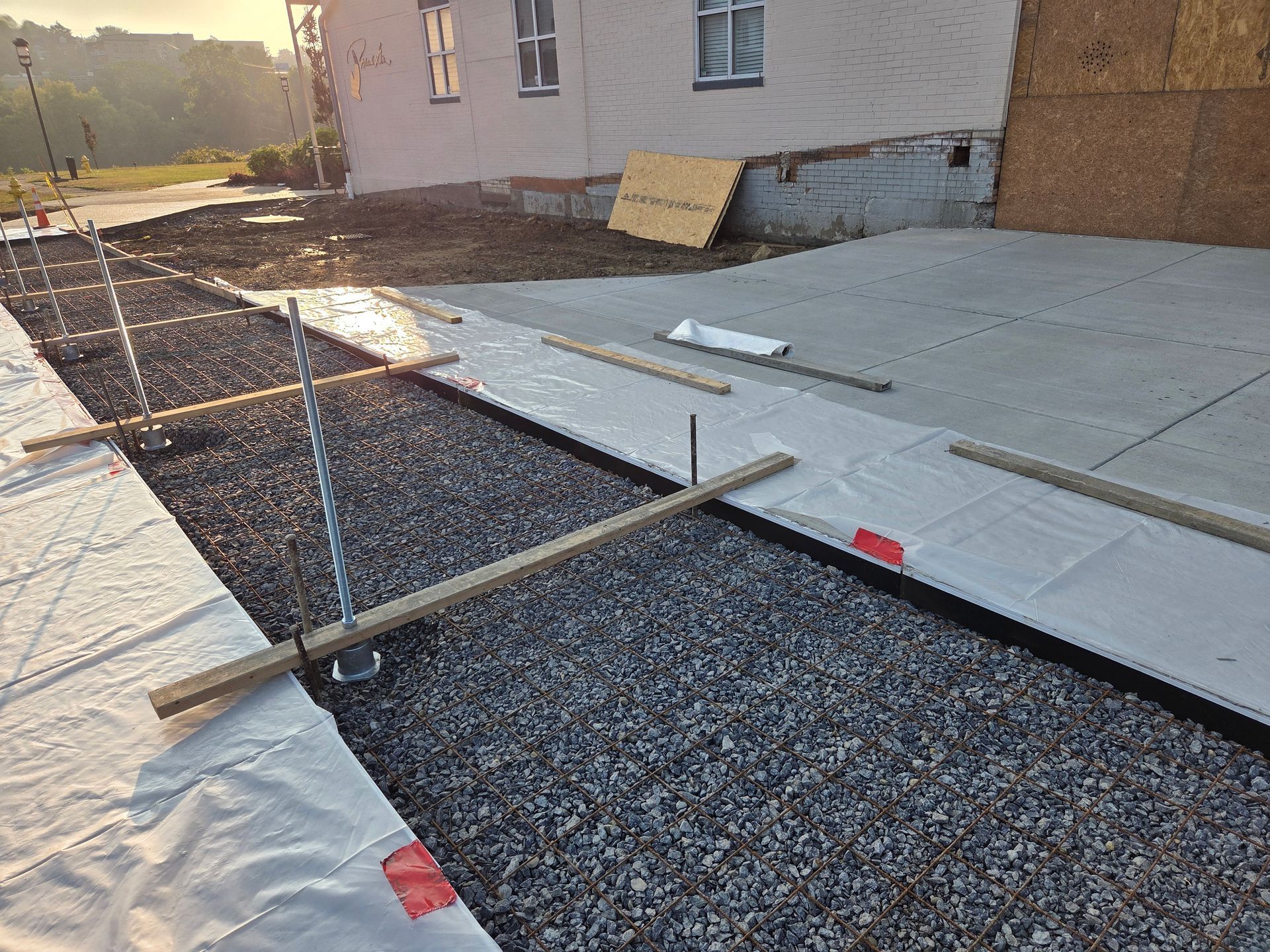 Concrete driveway construction in progress: gravel base, forms, and prepared section with reinforcing wire.