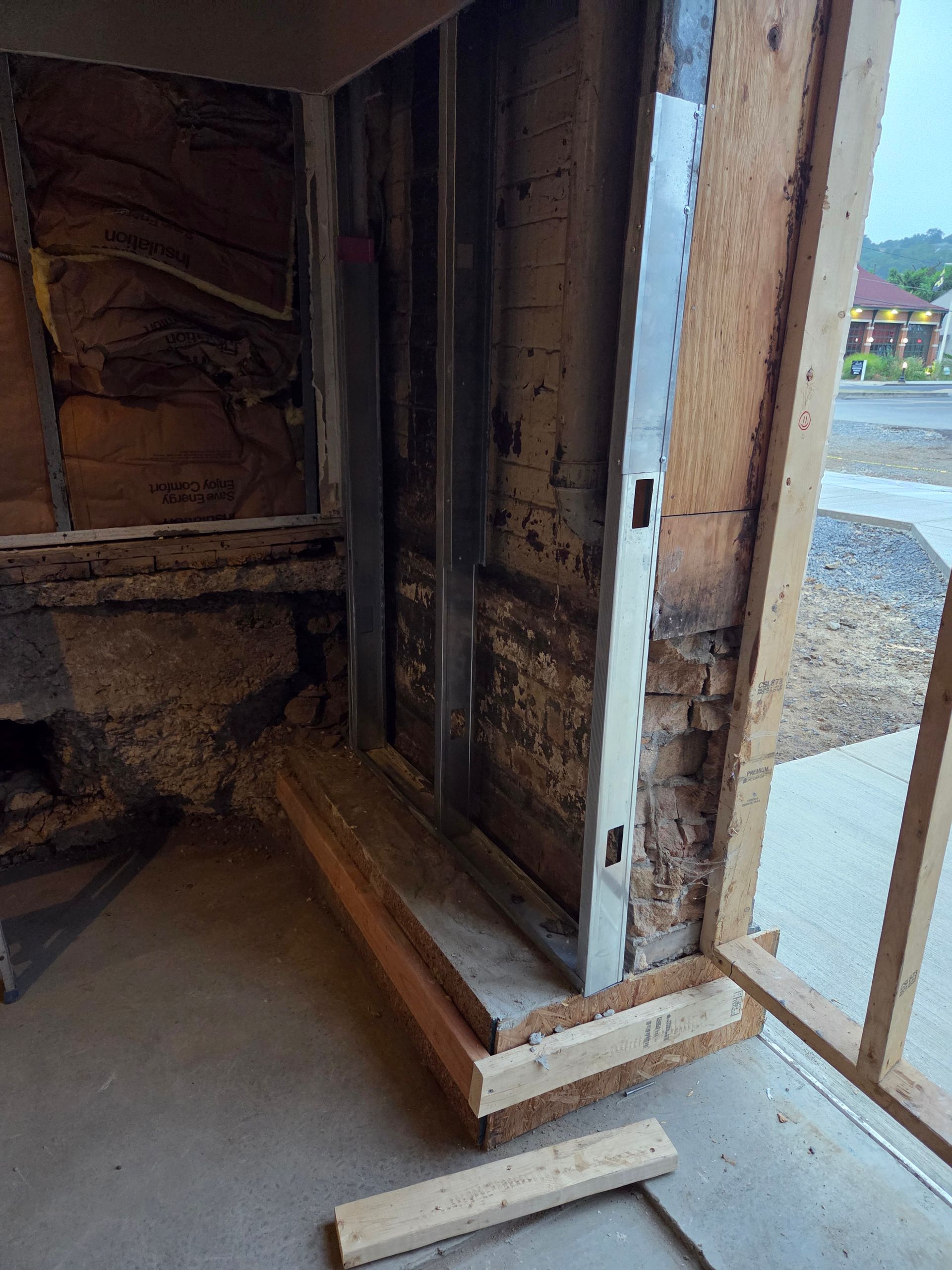 Interior view of a door frame under construction with exposed metal studs and wood framing.