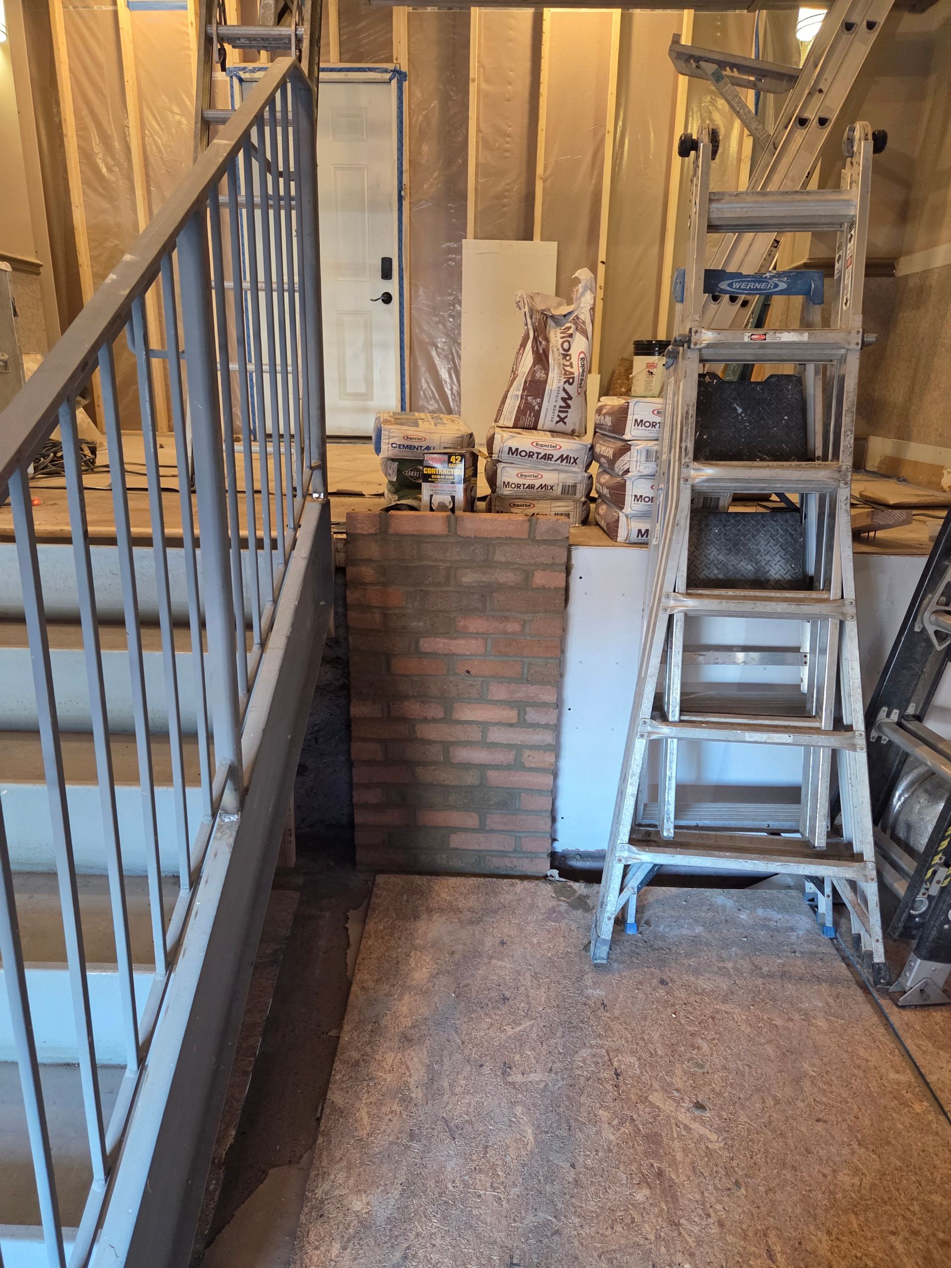 Construction area with stairs, ladder, and brickwork.