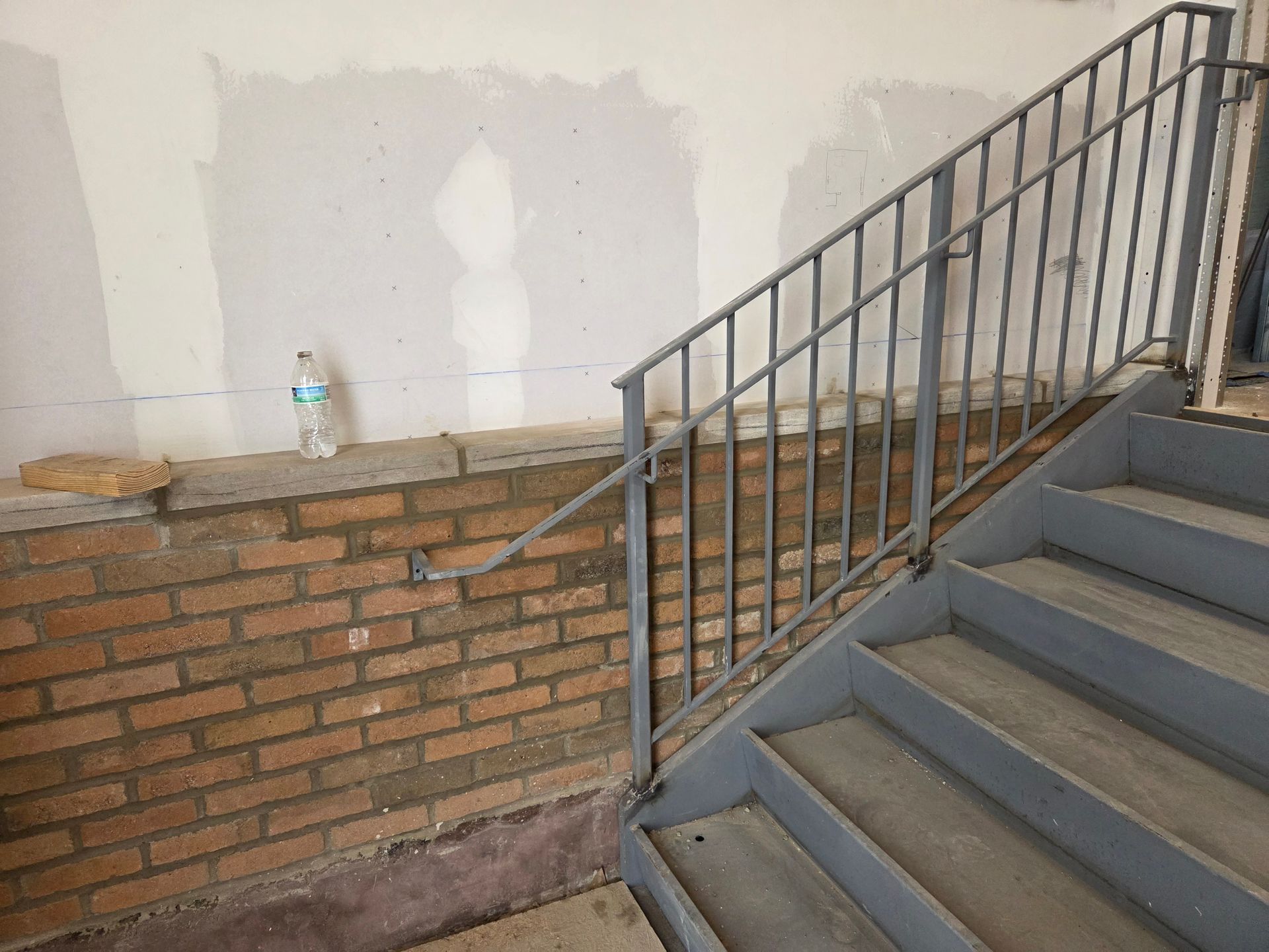 Brick wall and metal staircase with railing; bottle sits on the wall.