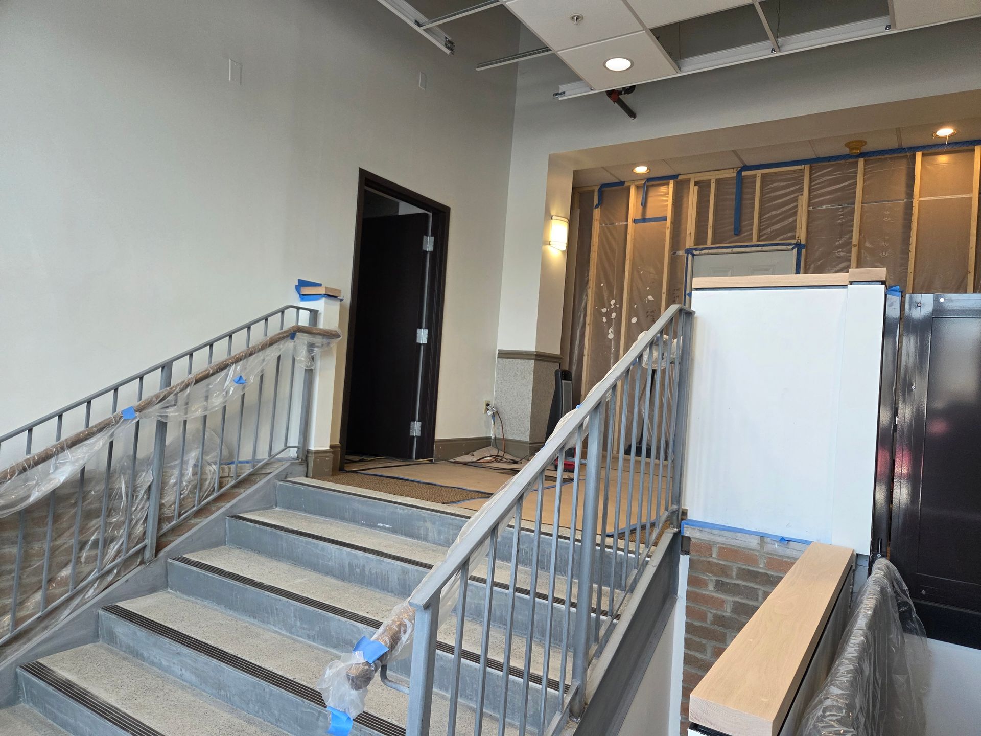Staircase under construction with metal railings, leading to a doorway, and partially finished walls.