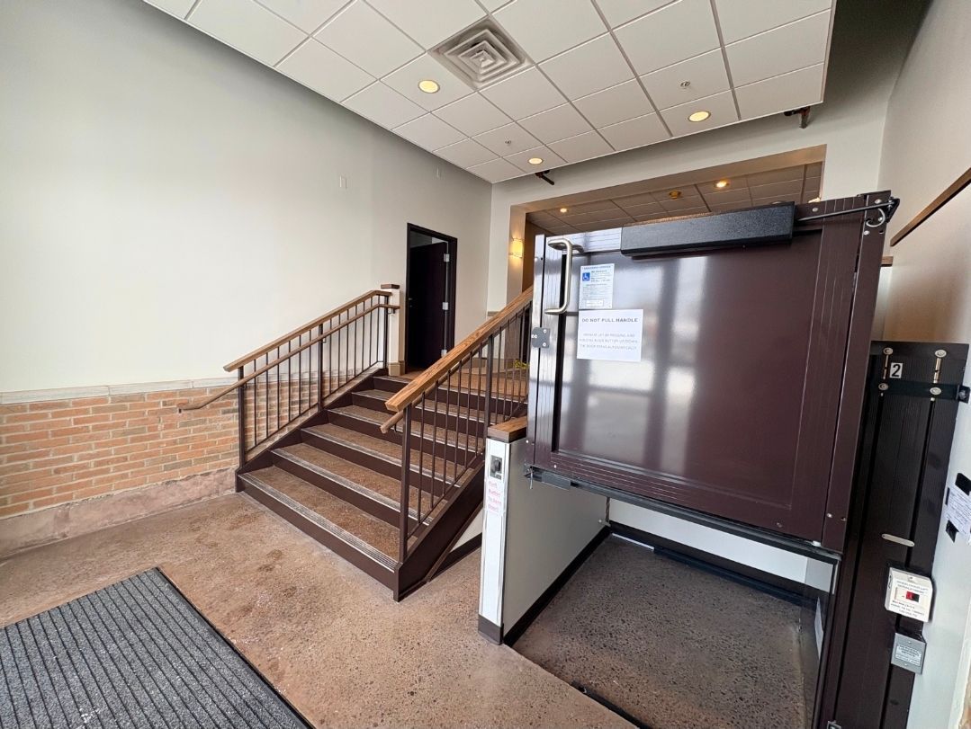 Interior view showing a staircase and a wheelchair lift next to it. Beige and brown tones.