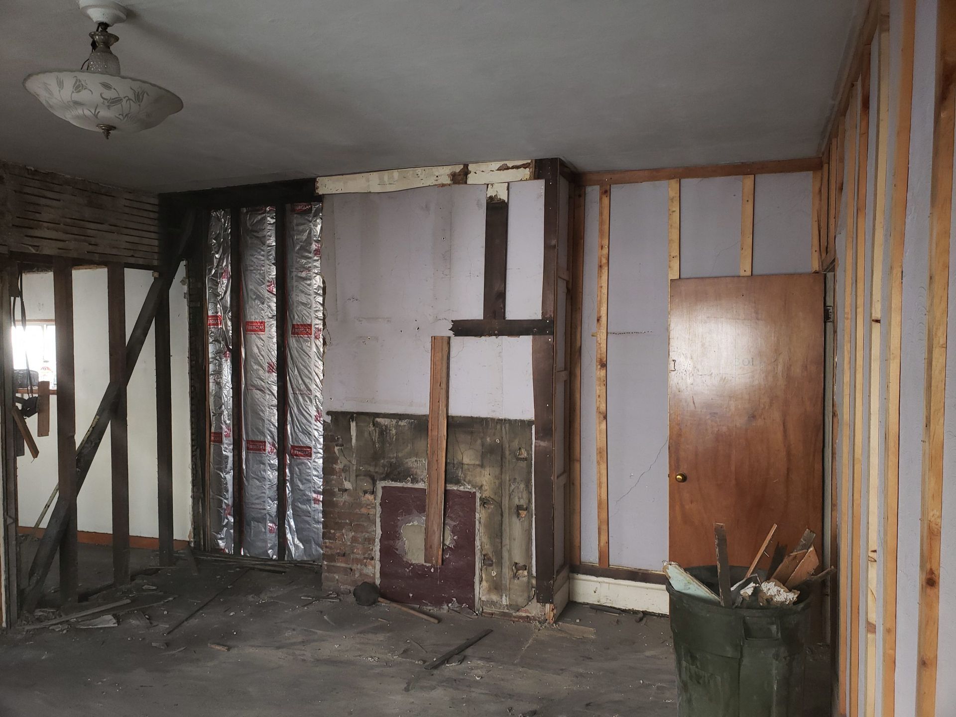 Room undergoing renovation; exposed wall studs, insulation, and partially removed drywall.
