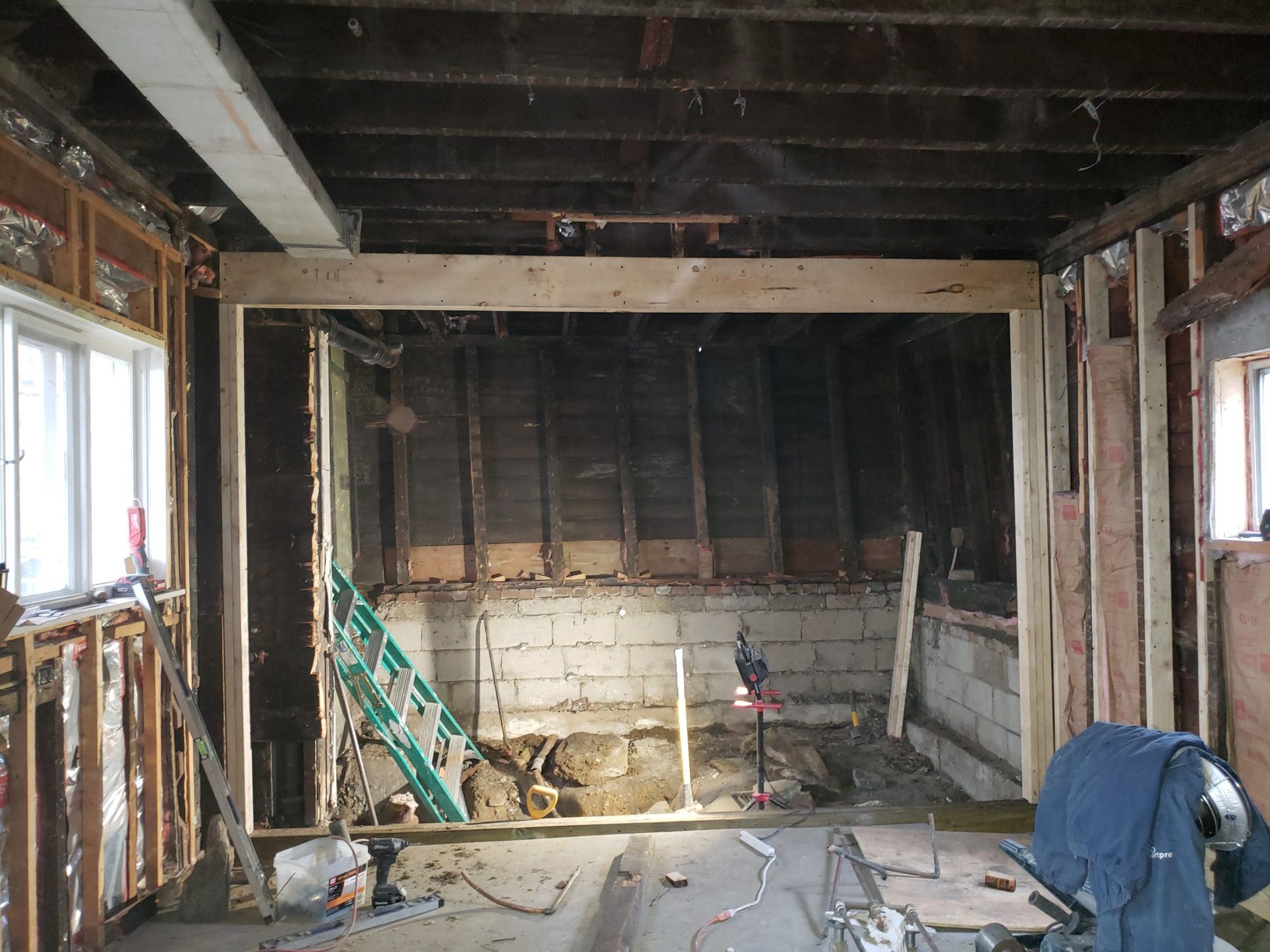 Room under construction; wooden beams frame a large opening. Exposed walls and ceiling.