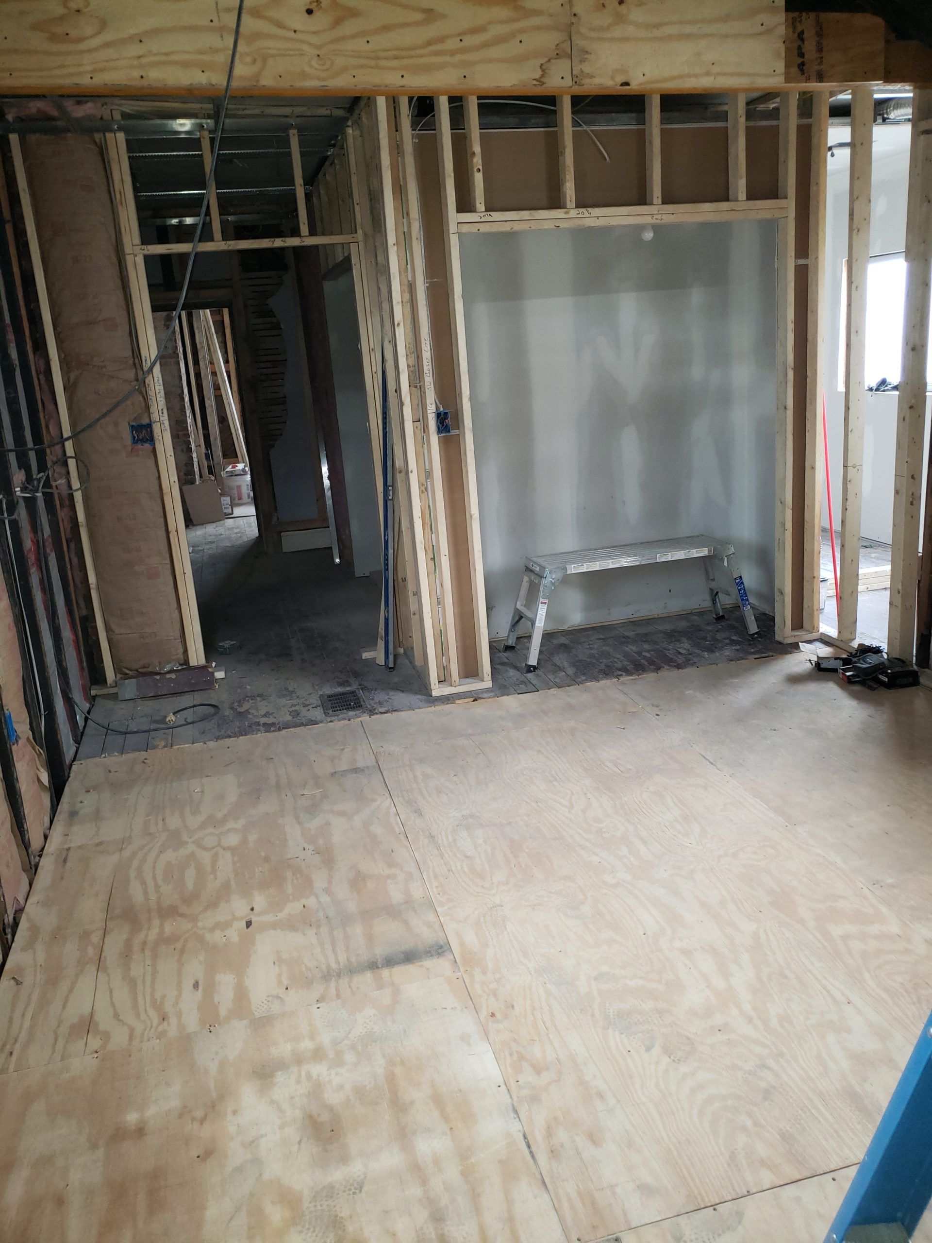 Interior of a building under construction, with wooden framing and plywood flooring.