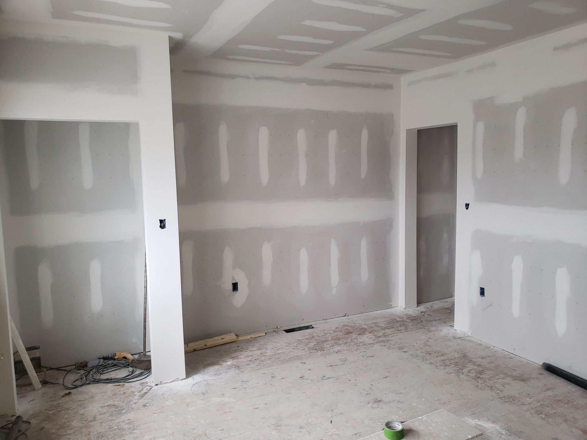 Room under construction with drywall installed on walls and ceiling.