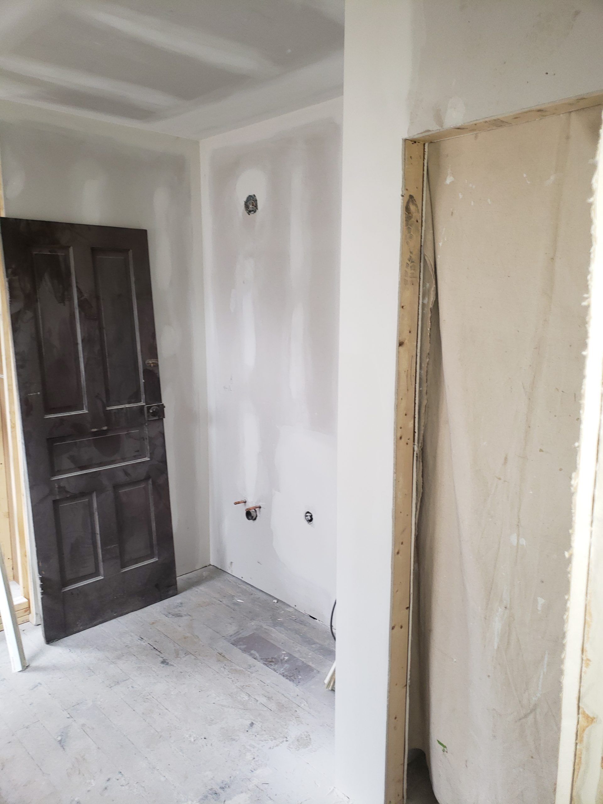 Room under construction with a dark door, drywall, and exposed framing.