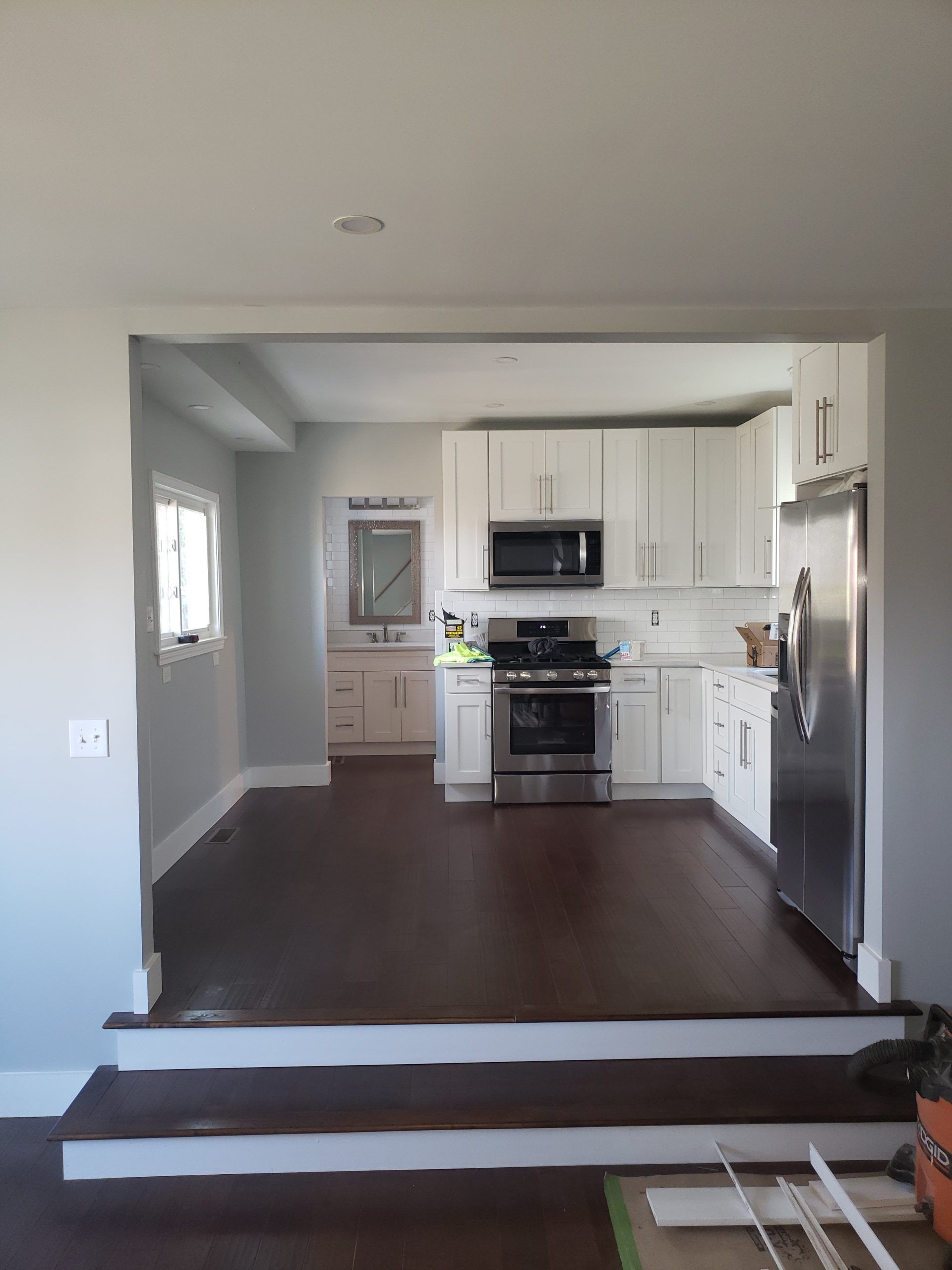 Kitchen with white cabinets, stainless steel appliances, and dark wooden floor.