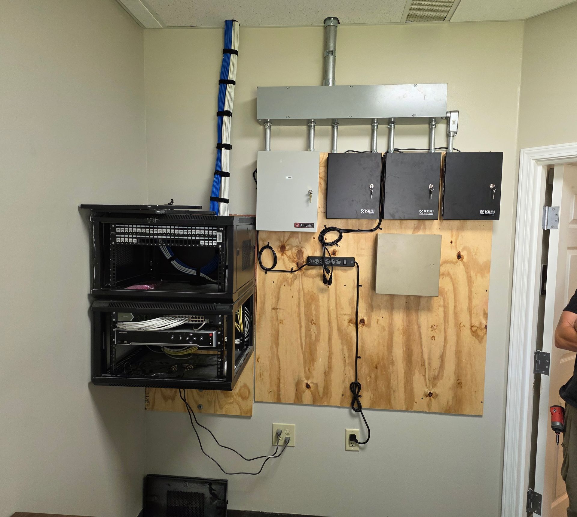Wall-mounted electrical equipment and wiring on a plywood panel in a utility room