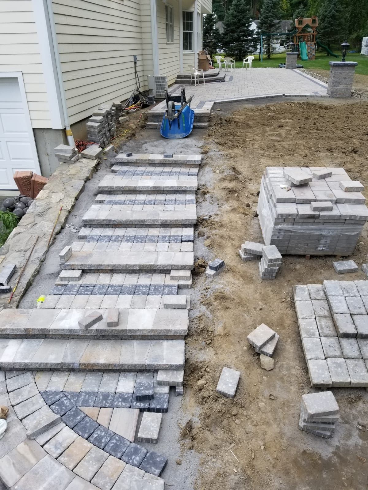 A brick walkway is being built in front of a house.
