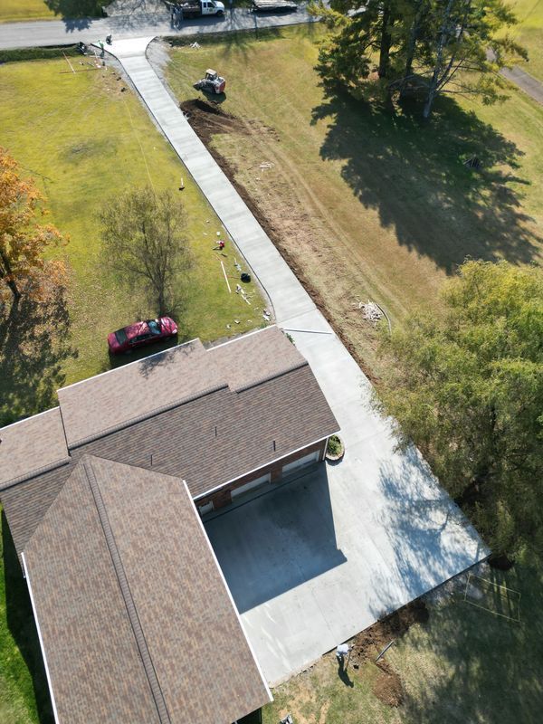 Aerial view of a house with a newly constructed concrete driveway extending to the street.