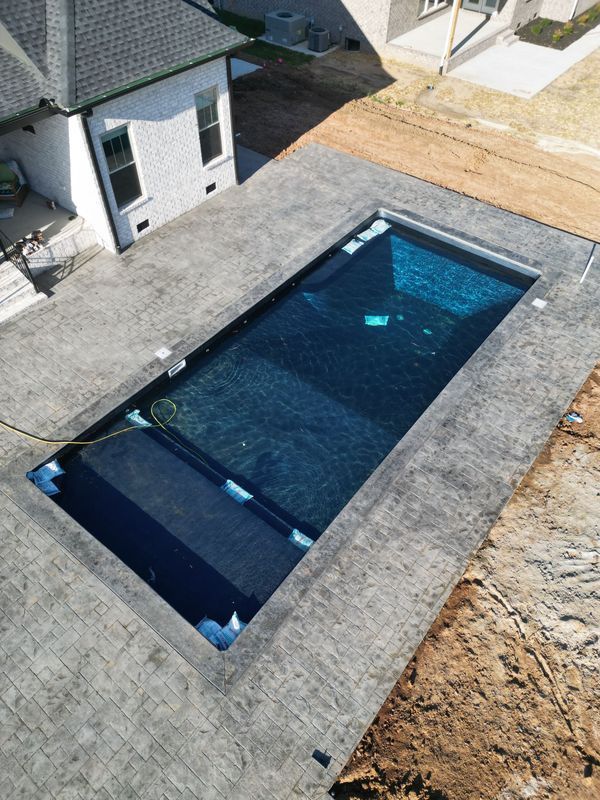 Rectangular swimming pool with dark blue water and gray concrete surround.