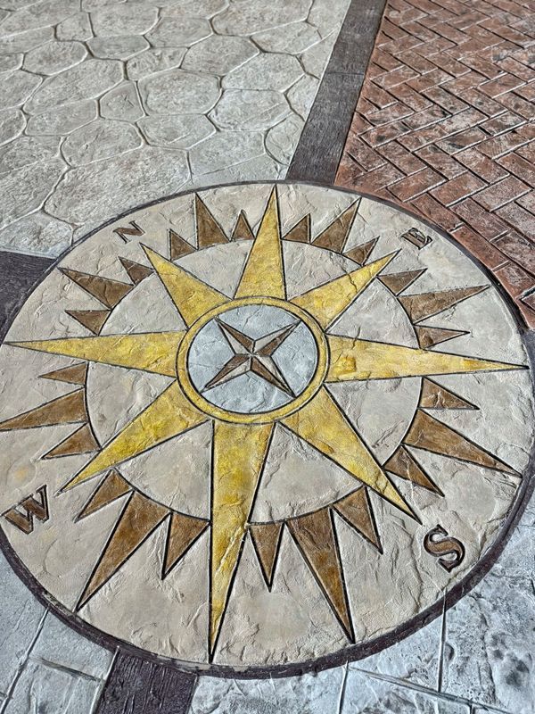 Compass rose design embedded in outdoor paving, with the cardinal directions labeled.