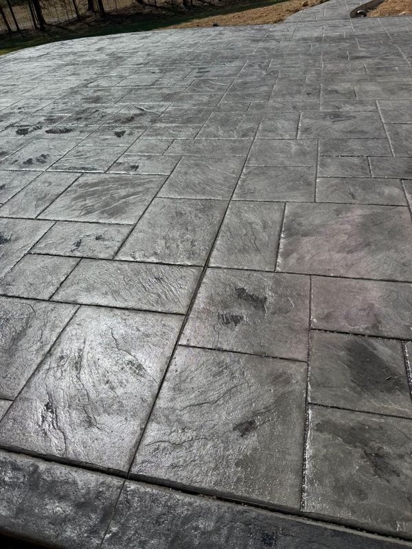 Gray stamped concrete patio with rectangular and square tile pattern.