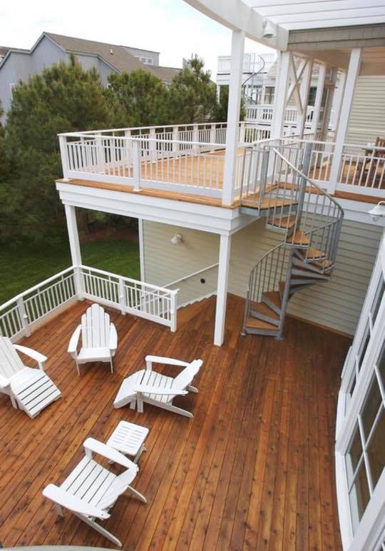 A wooden deck with chairs and a spiral staircase