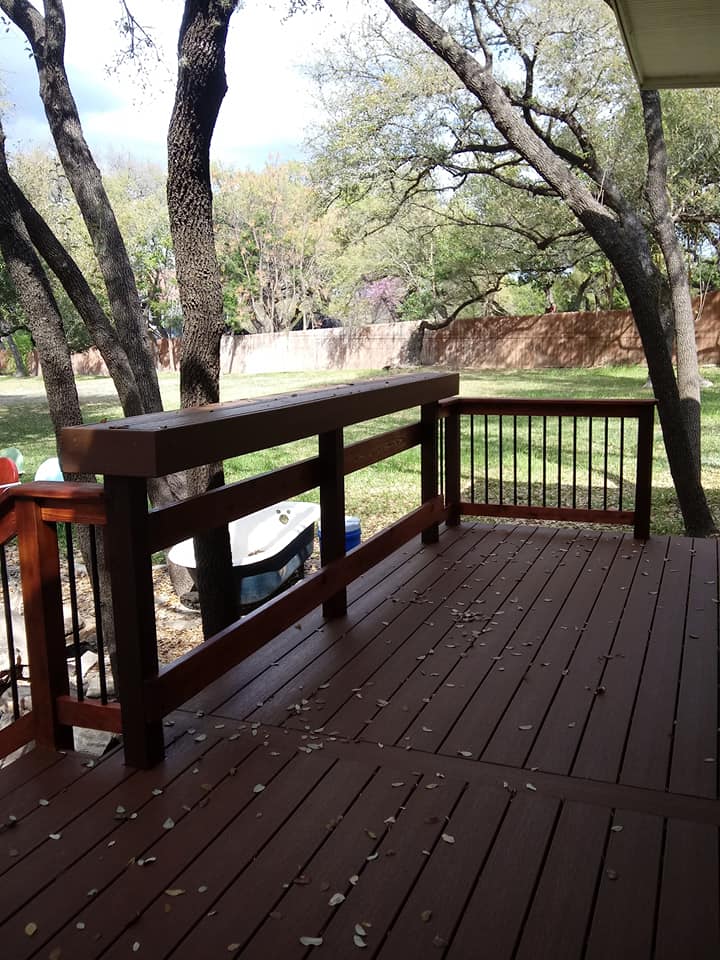 A wooden deck with a railing and trees in the background