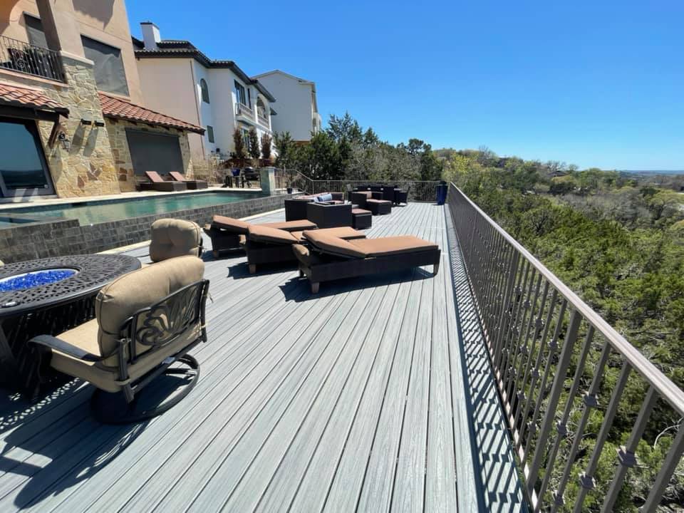 A large deck with chairs , a table and a fire pit.