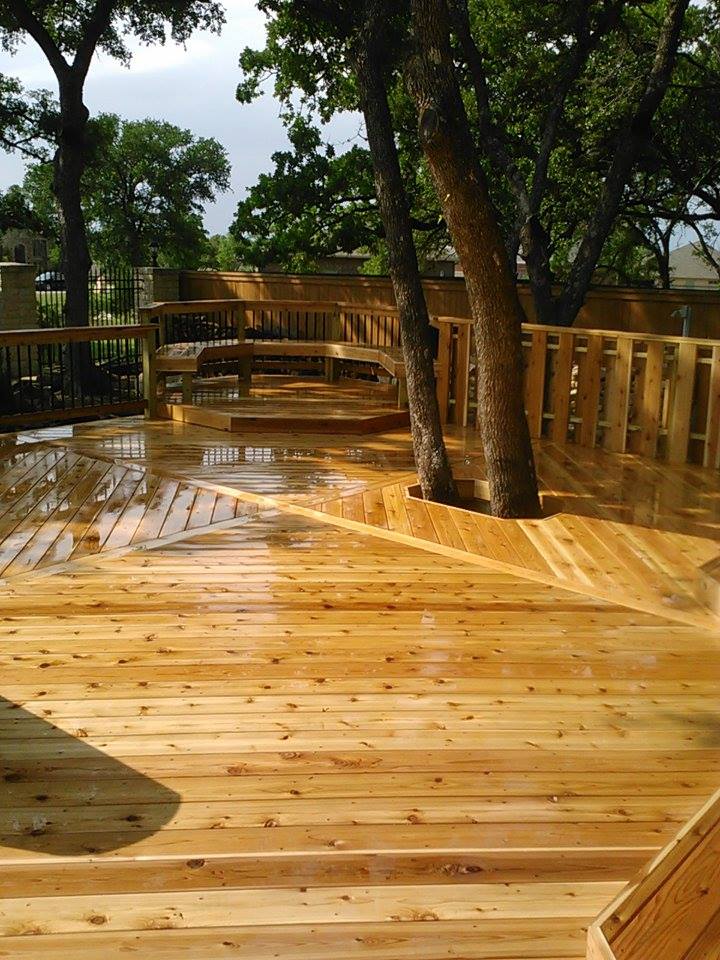 A wooden deck with a railing and trees in the background