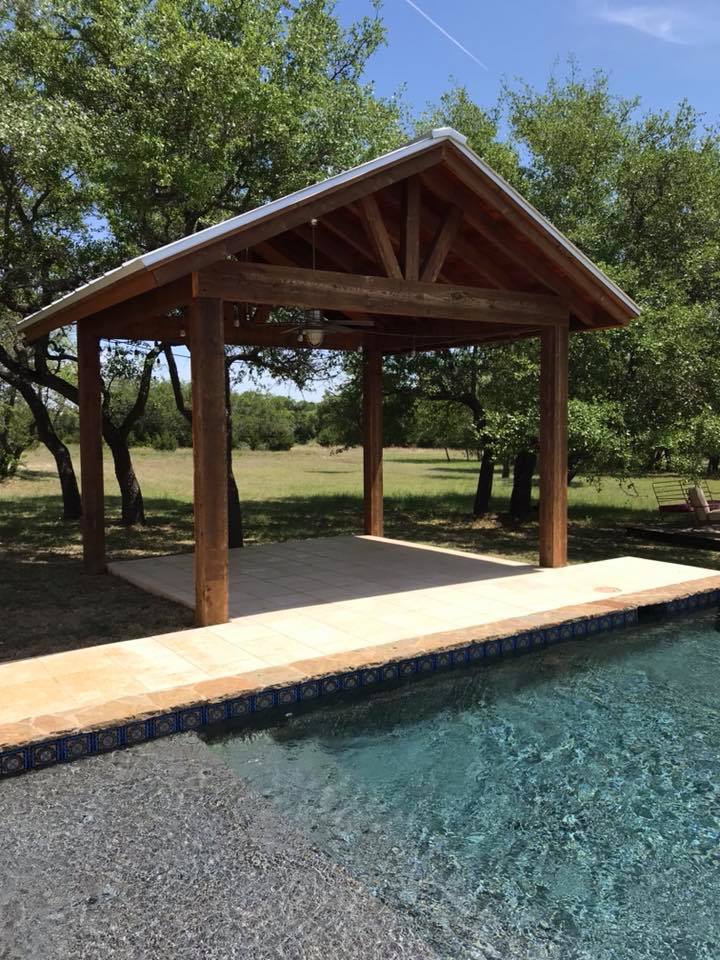 A wooden pavilion is sitting next to a swimming pool.