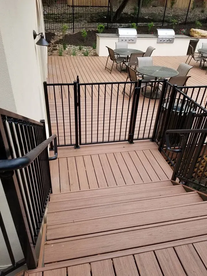 A wooden deck with tables and chairs and a grill