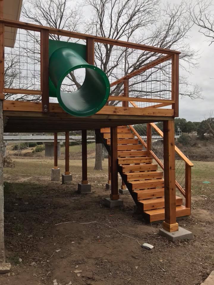 A wooden deck with stairs and a green slide