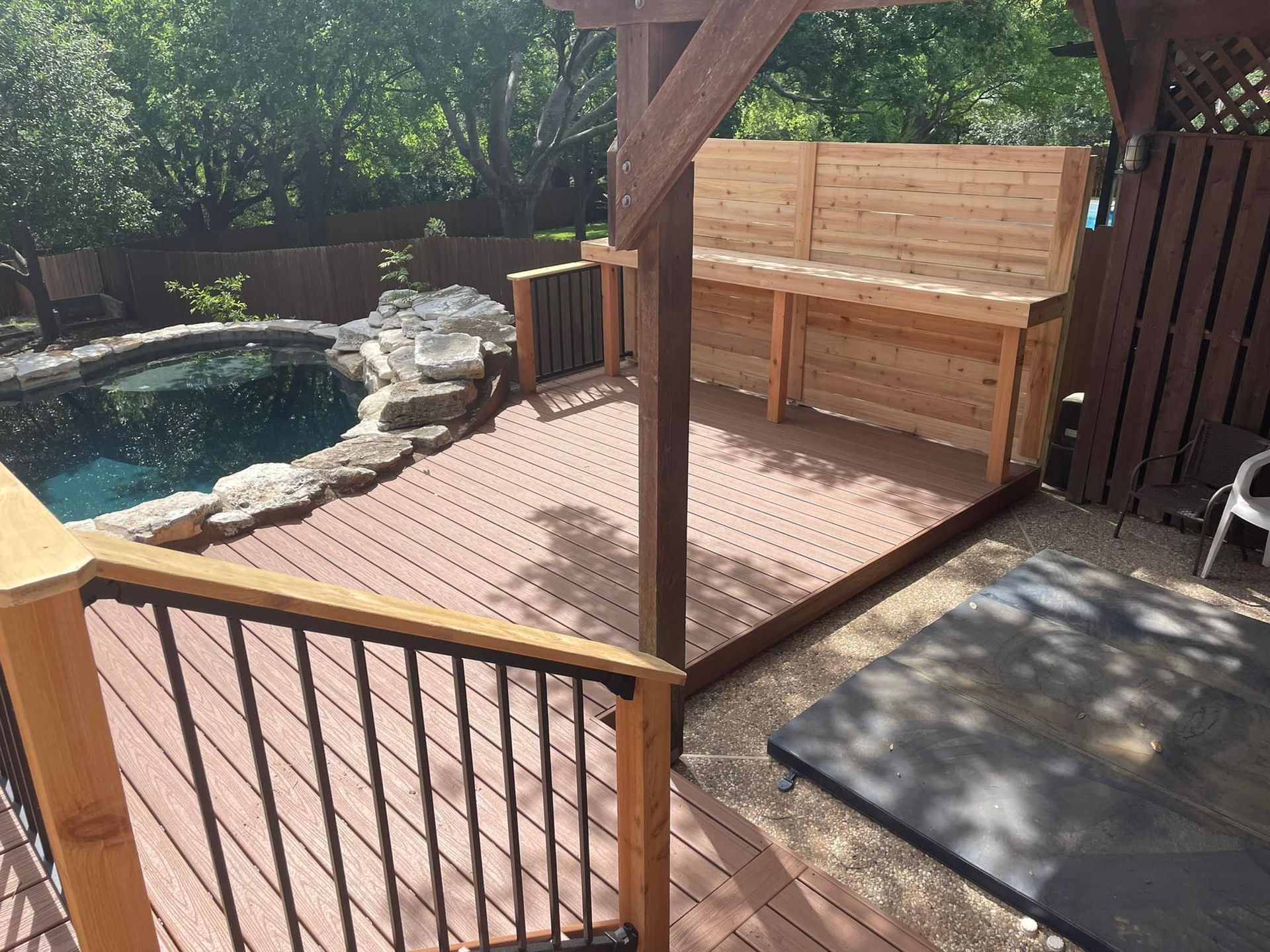 A wooden deck with a gazebo and a pool in the background.