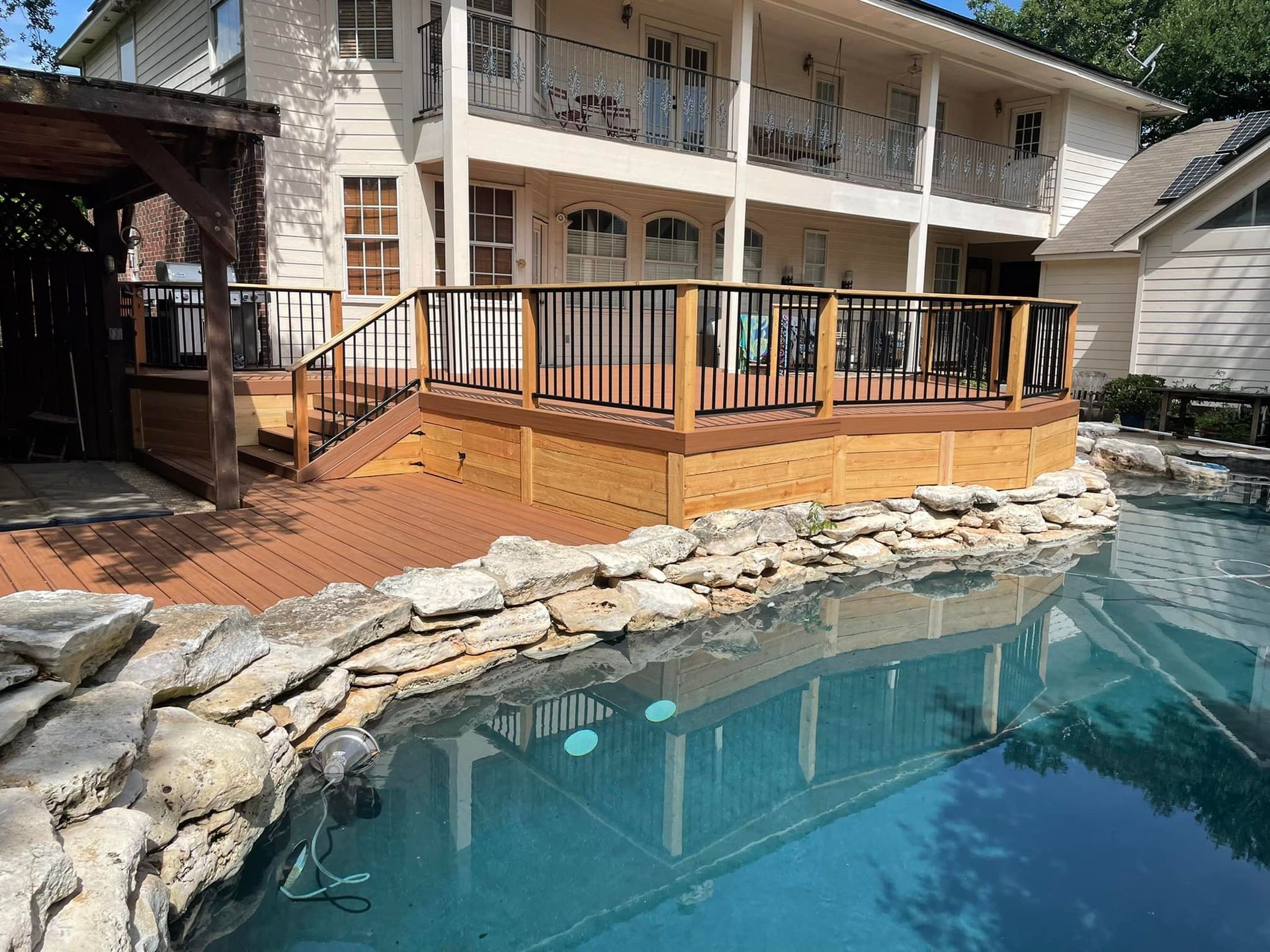 A large house with a swimming pool and a wooden deck.