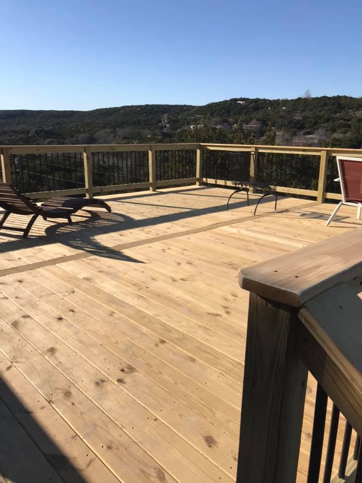 A wooden deck with chairs and a table on a sunny day.