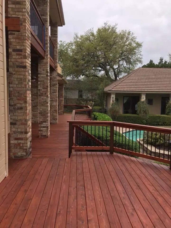 A large wooden deck with a pool in the background