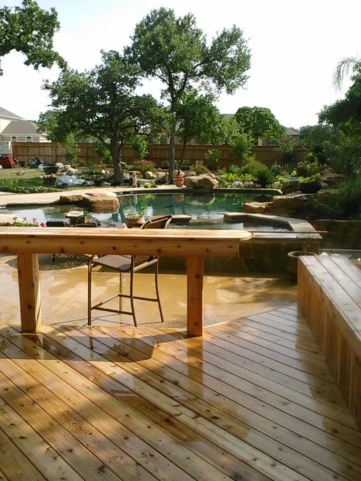 A wooden deck with a swimming pool in the background