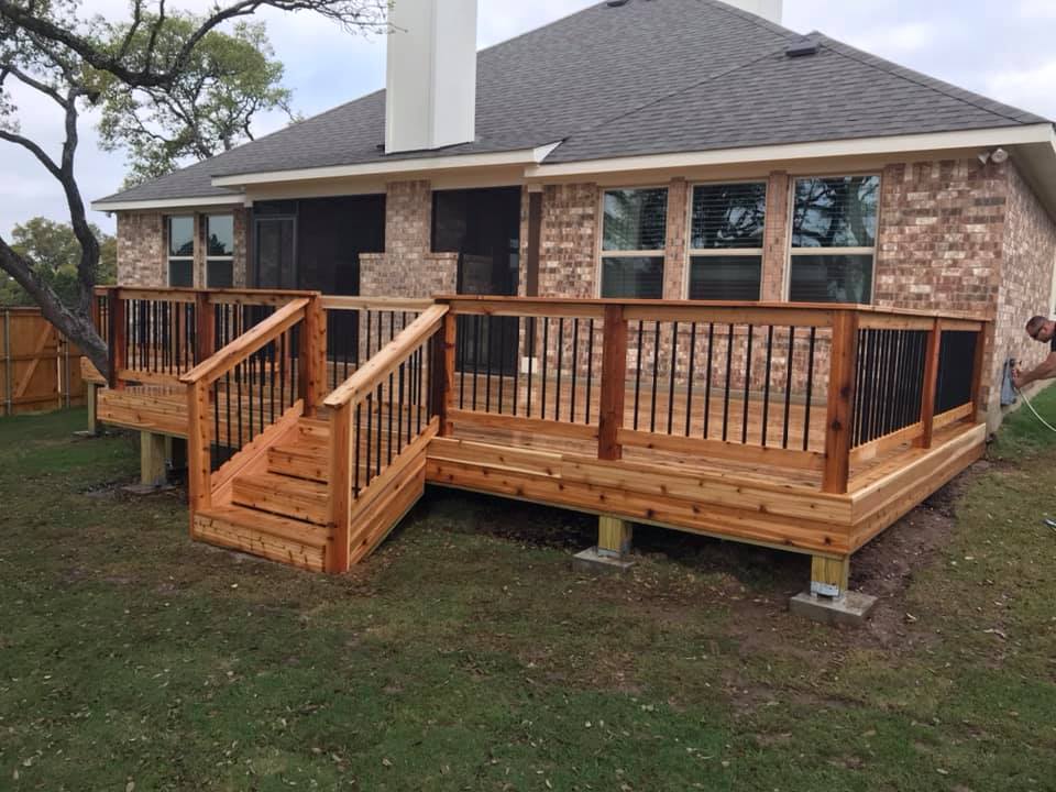 A wooden deck with stairs is in front of a brick house.