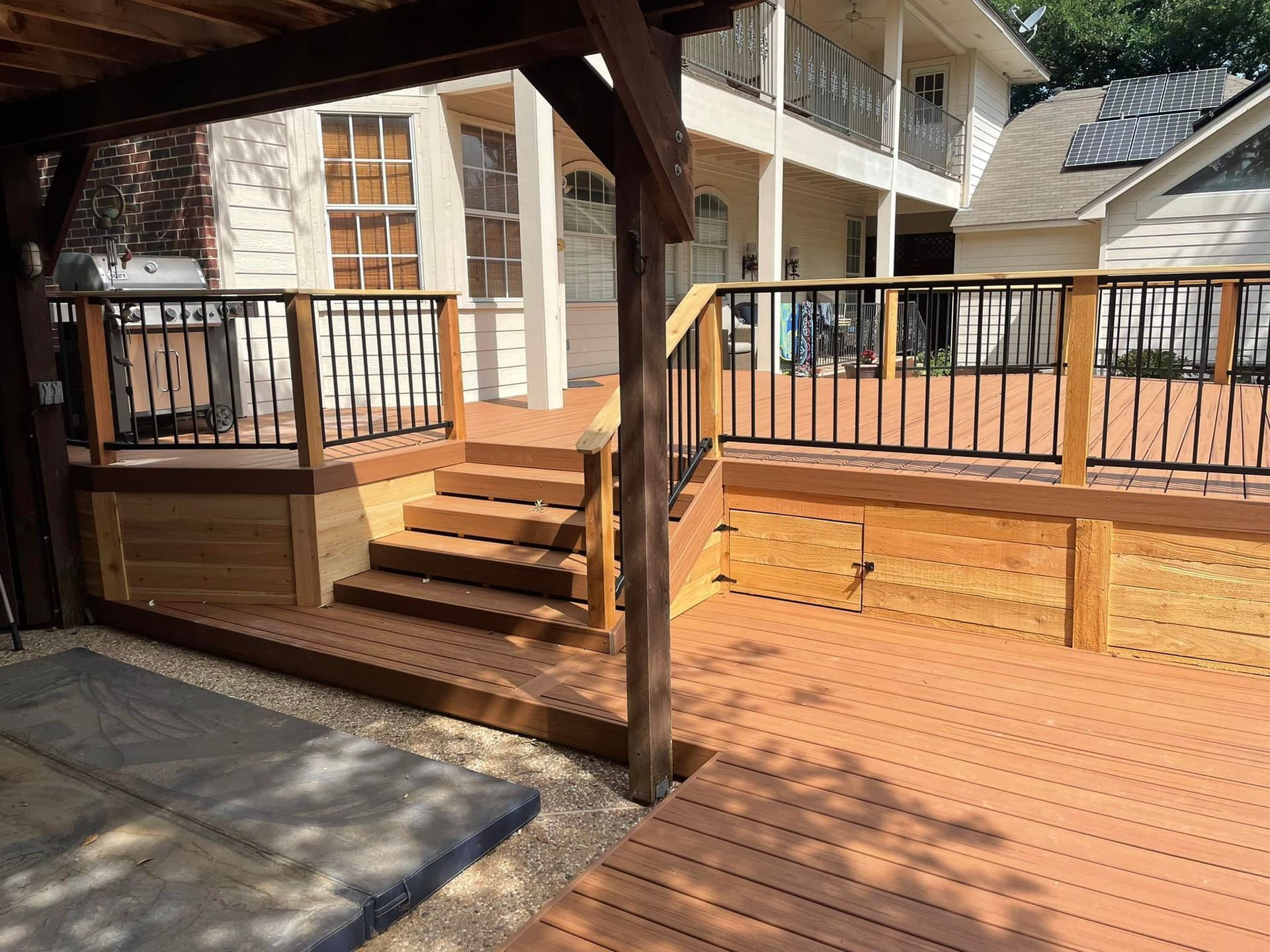 A wooden deck with stairs and a railing in front of a house.
