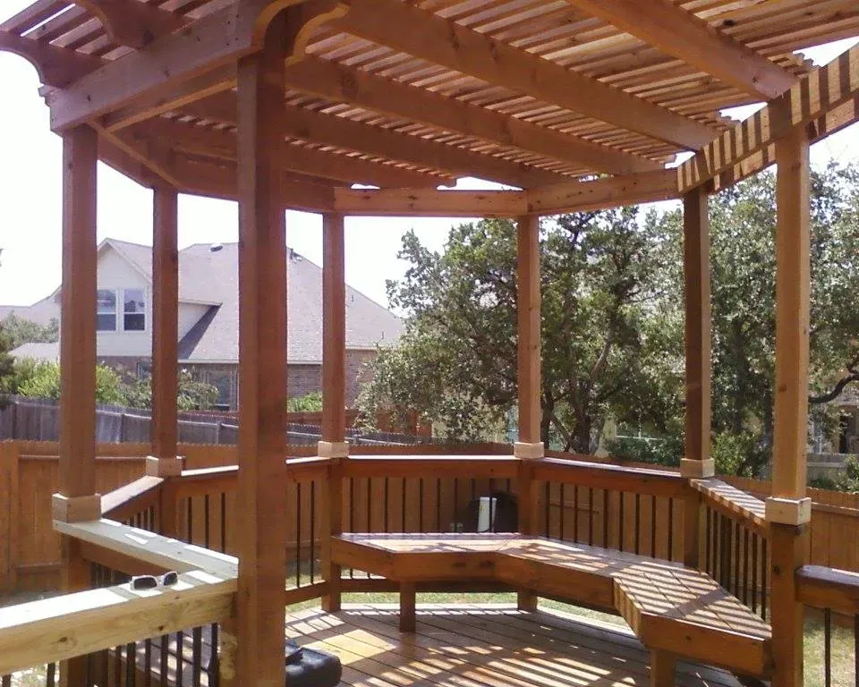 A wooden gazebo with a curved bench underneath it