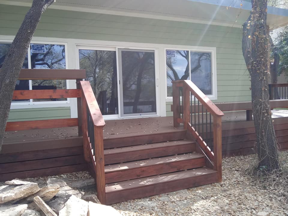 A green house with a wooden deck and stairs